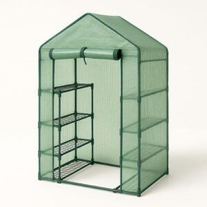 Walk-in mini greenhouse with a green PE cover, roll-up zippered door, and metal frame featuring tiered wire shelves, displayed on a bright white background with a soft shadow.