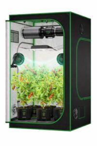 Indoor grow tent with LED grow light, carbon filter, ventilation fans, and healthy pepper plants growing in fabric pots.